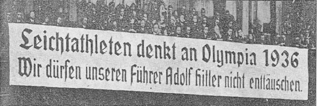 A banner, written in German, hangs over the front of a tier of the German training stadium