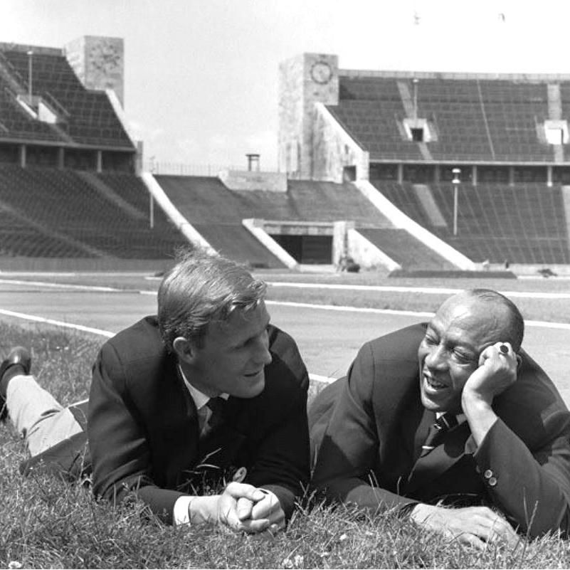 Kai Long and Jesse Owens lie on the grass at Berlin's Olympic Stadium