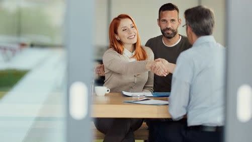 A couple shakes hands with their financial advisor at the end of a meeting with him.