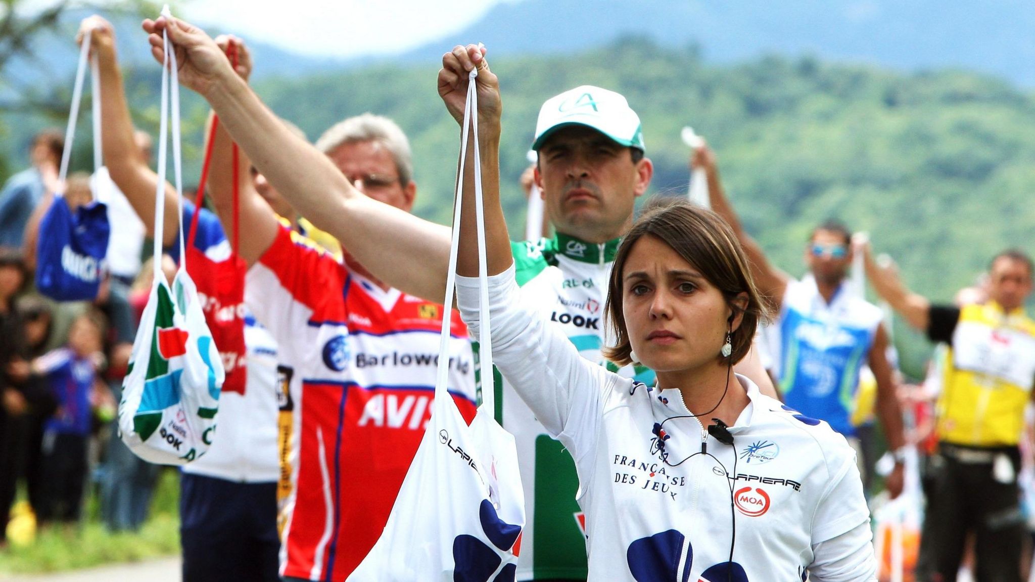 Team soigneurs hand out bags on the roadside of the Tour de France