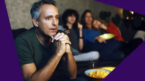 Getty Images Man with family watching TV