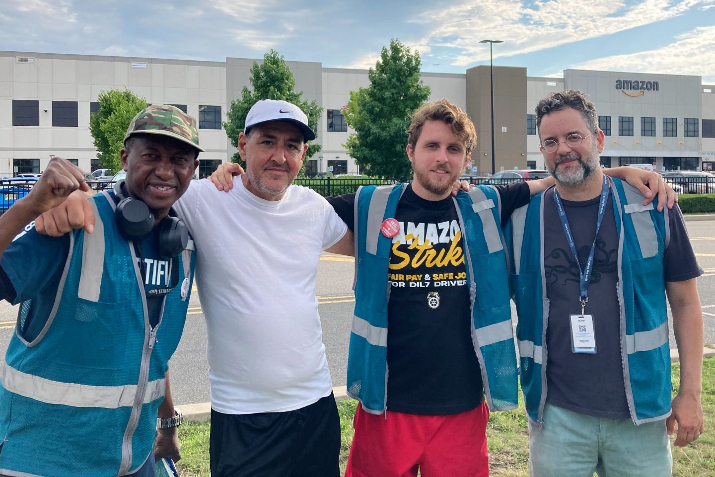 Four men pose outside Amazon warehouse