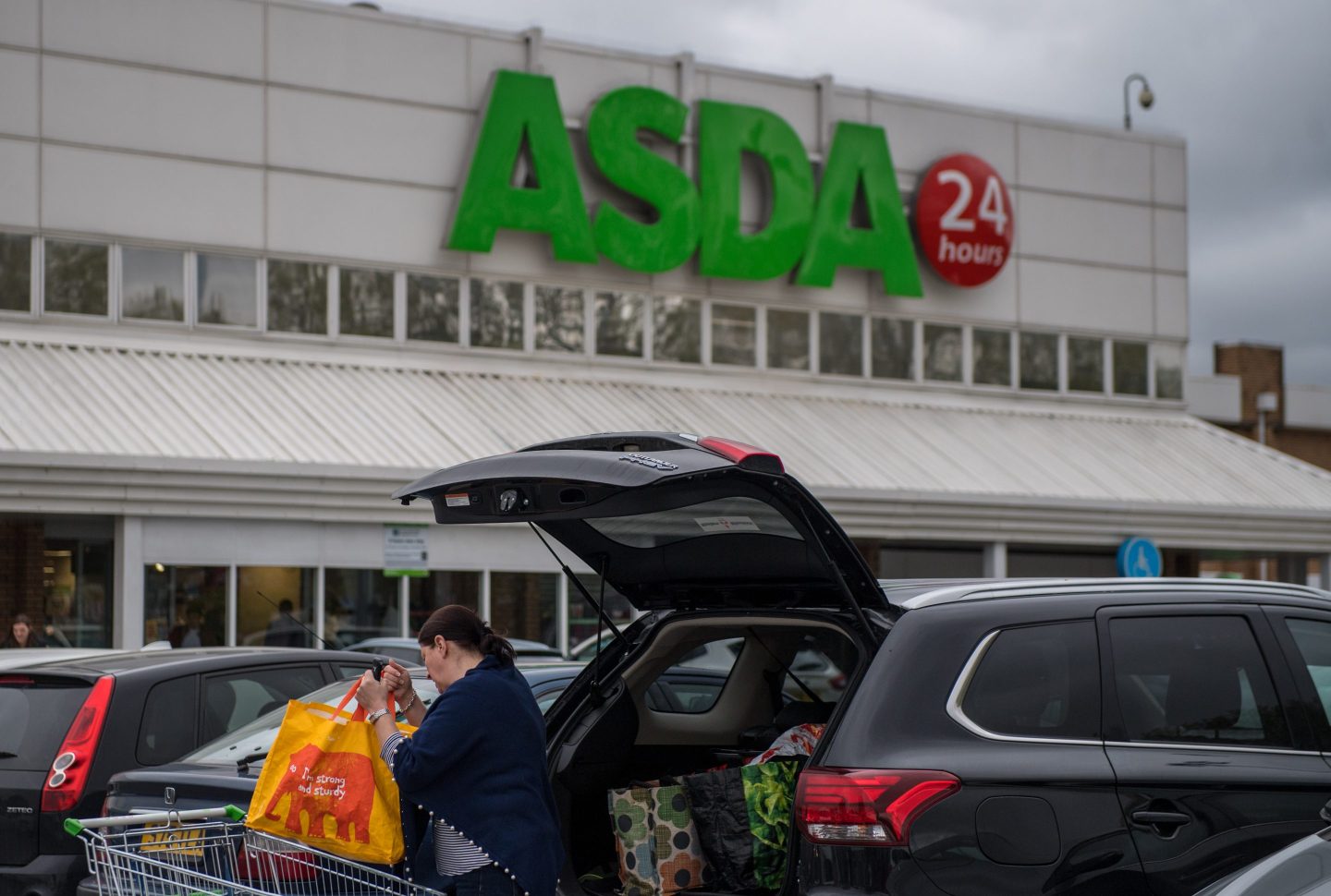 LONDON, ENGLAND - APRIL 29: A woman loads her food shopping from Asda in Sainsbury's bags into her car in the car park at an Asda supermarket on April 29, 2018 in London, England. Major supermarket chains Sainsbury's and Asda have been reported to be in talks over a £10 billion merger deal which would mean the possible new supermarket group would have 31.4% market share, compared with Tesco's 25.6%. (Photo by Chris J Ratcliffe/Getty Images)