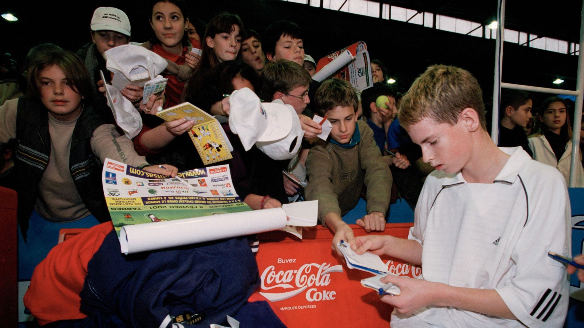 Andy Murray surrounded by autograph hunters at a youth tennis tournament