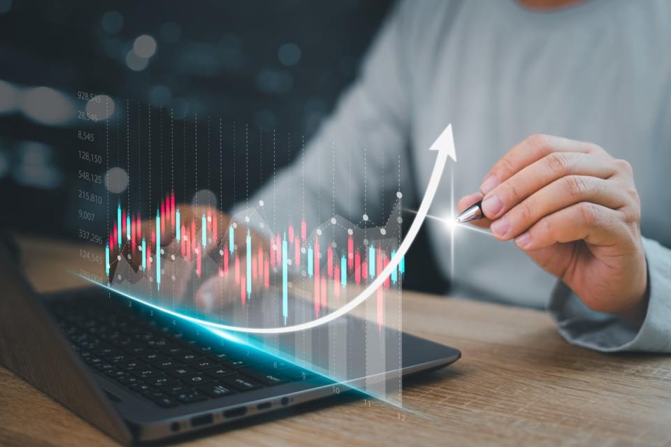 A hand tracing a holographic stock chart.