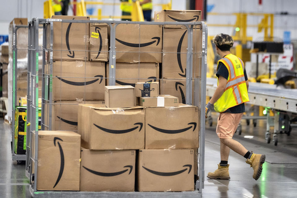 An Amazon employee walks past load Amazon packages on a cart on the floor at Amazon's DAX7 delivery station during Amazon's annual Prime Day event on Tuesday, July 16, 2024, in South Gate, Calif. (AP Photo/Richard Vogel)