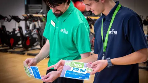 NHS England Staff at Better gym holding the new sticker