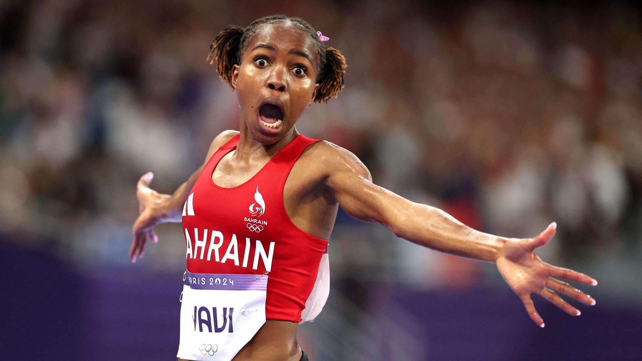 Winfred Yavi stretches her arms out and looks in stunned wonderment at the camera after winning the women's 3000m steeplechase at the Paris 2024 Olympics