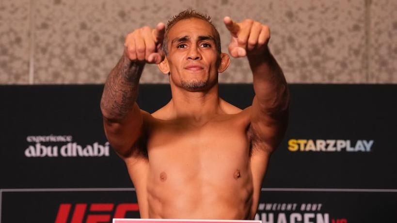 Tony Ferguson smiles and points as he weighs in