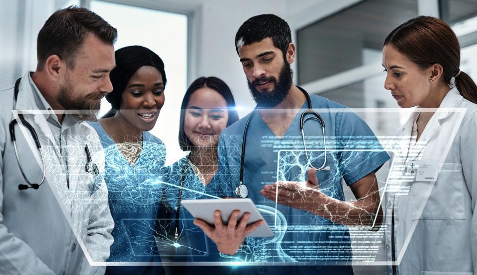 Healthcare workers gather around a digital display.