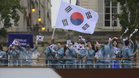 Getty Images South Korean athletes wave flags while standing on a boat