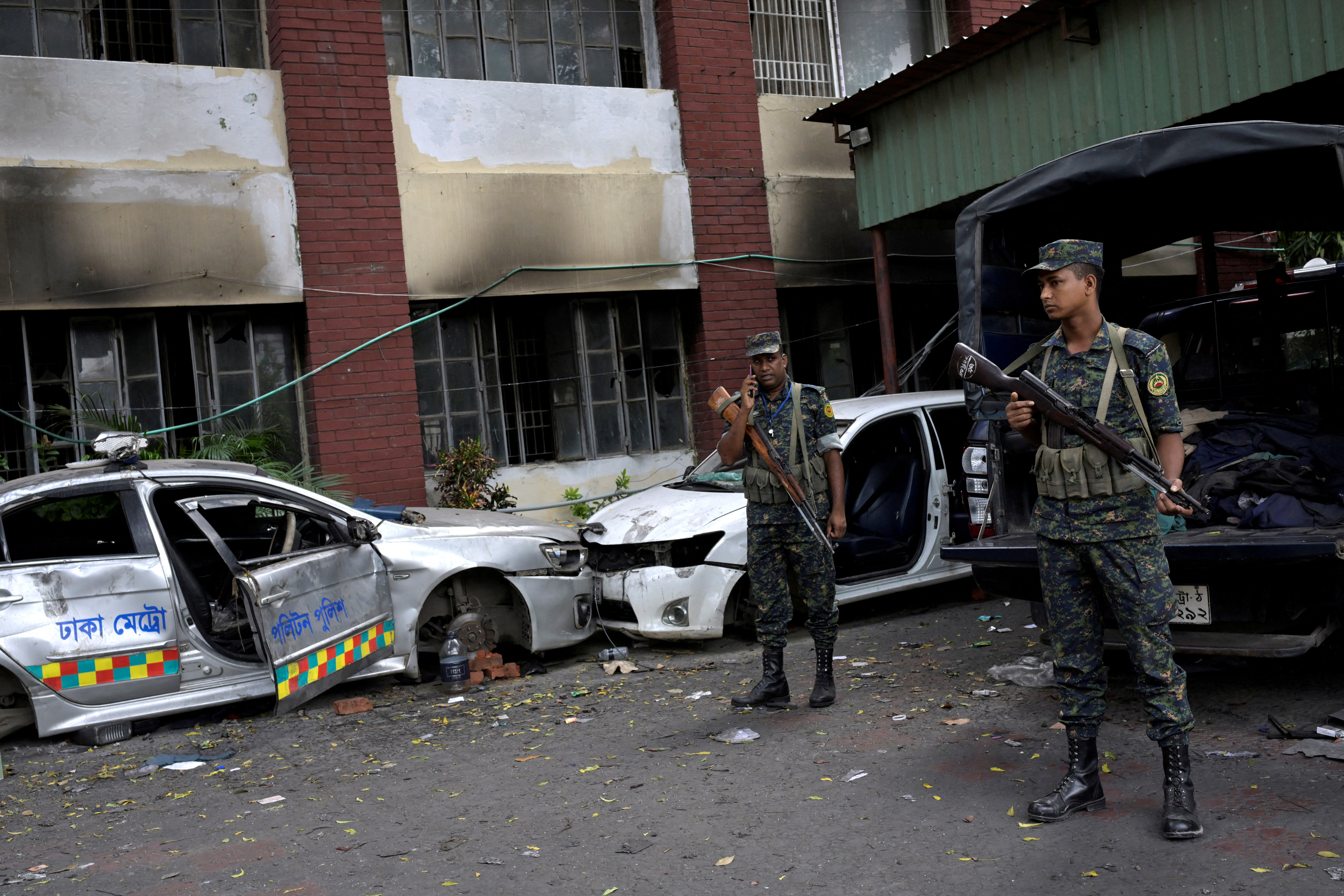 © Reuters. Security force personnel stand guard next to damaged vehicles outside a police station, days after the resignation of former Bangladeshi Prime Minister Sheikh Hasina, in Dhaka, Bangladesh, August 8, 2024. REUTERS/Fatima Tuj Johora 