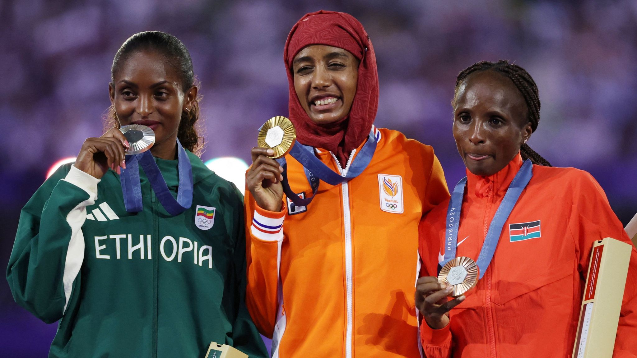 Sifan Hassan stands on the podium with her gold medal