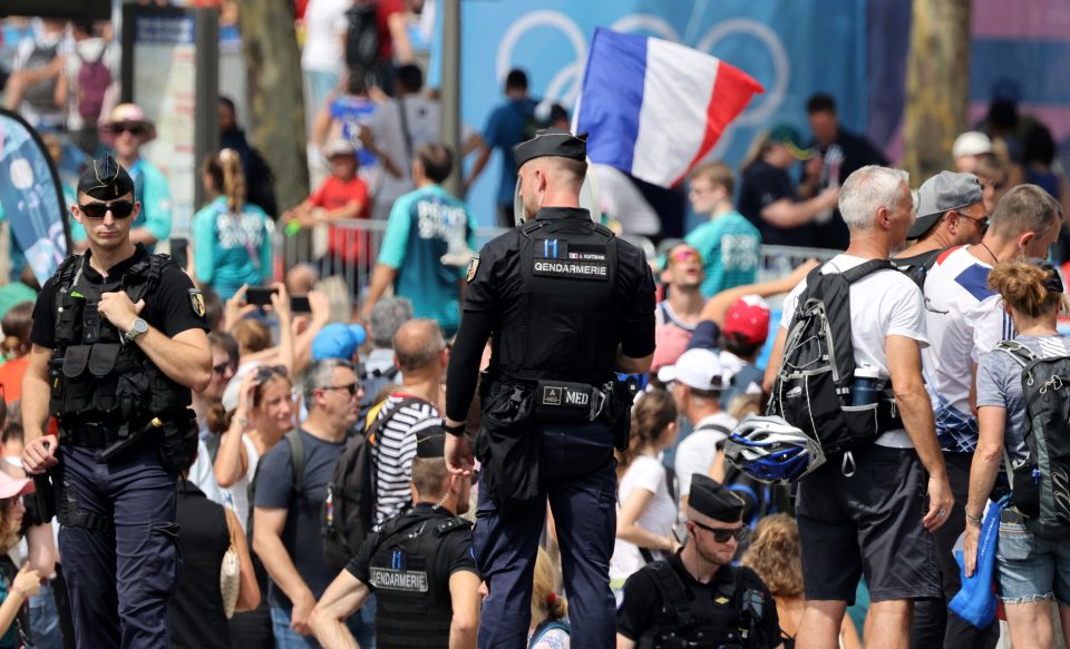 French gendarmes look on as spectators watch the progress of athletes during the triathlon programme of the Paris 2024 Olympic Games in central Paris on July 31, 2024. The Olympic triathlon programme finally set off in the River Seine, providing huge relief for organisers after problems with water quality marred the run-up to the competition. Organisers were forced to cancel training this week in the river and postponed the men's race on July 30, after the Seine was found to be too dirty for athletes following rainstorms last week. But despite heavy rain overnight, which can stir up pollution, organisers early on July 31, said that the water levels had been 