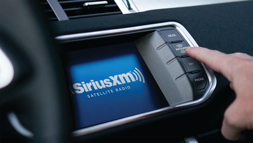 A person pressing the satellite radio button on their in-vehicle dashboard. 