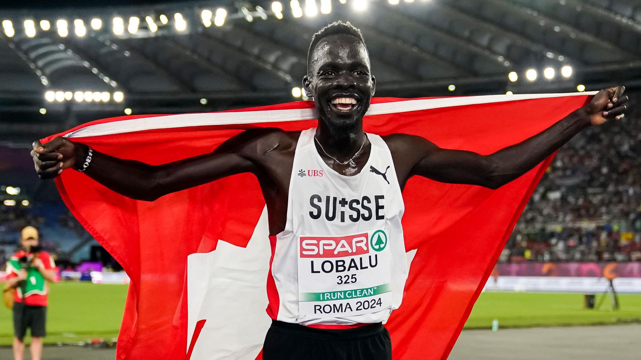 Lobalu holds the Swiss flag after winning gold in the 10,000m at the European Championships in Rome.