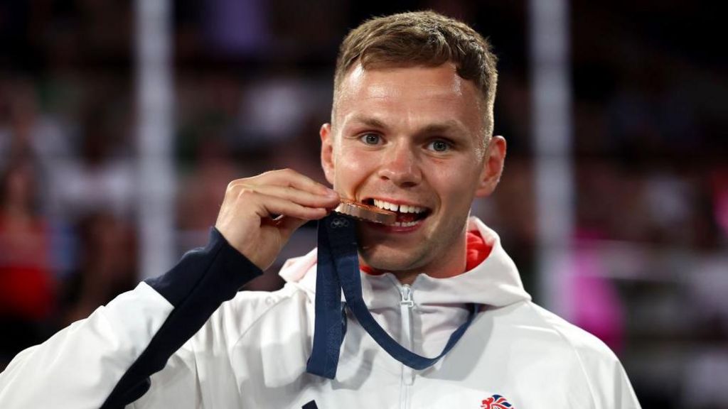 Lewis Richardson bites on his bronze medal in Paris 