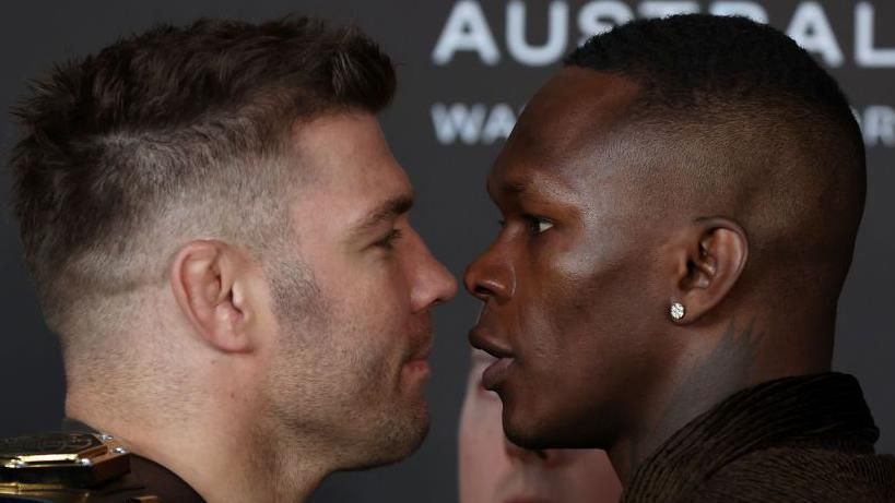 Dricus Du Plessis smirks as he faces off with Israel Adesanya at a news conference