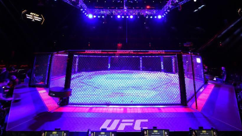 A cageside view of the UFC's octagon lit up in the darkness