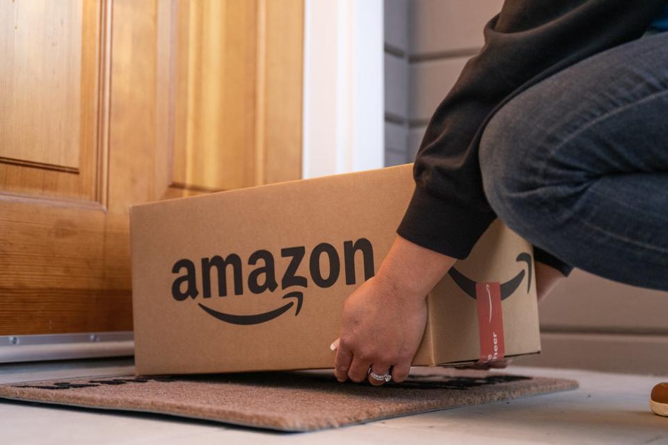 A person placing an Amazon package at a doorstep. 