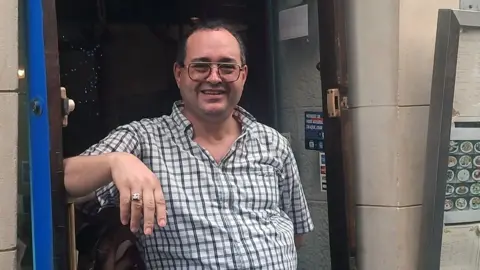 Riad stands in the doorway of his restaurant