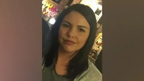 Family handout Alice Webb is smiling at the camera, she has dark hair and a piercing in her lower lip. She stands in front of an illuminated bar.