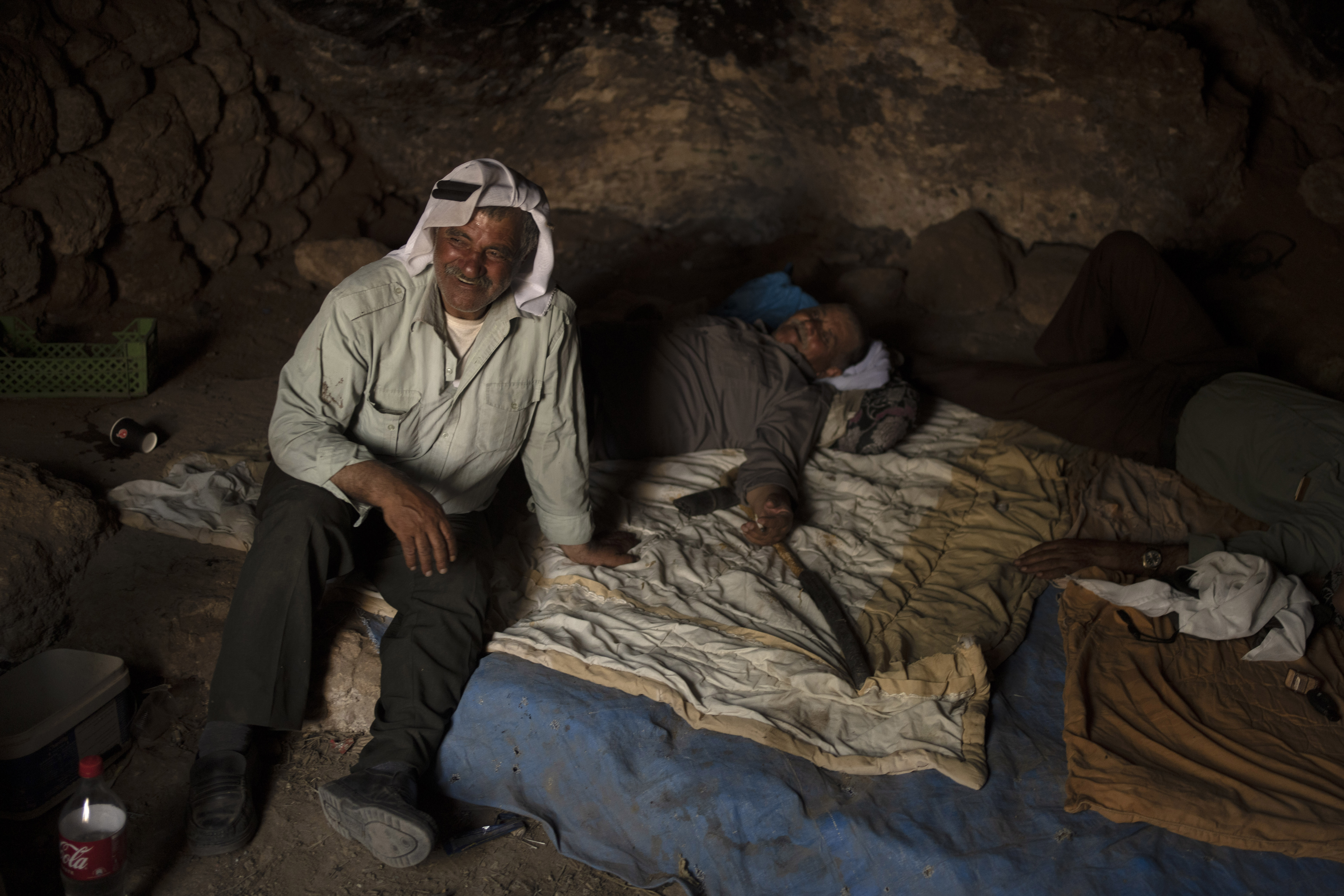 Palestinians Ribhi Ahmad Battat, left, and Issa Ahmad Battat, residents of the West Bank village of Khirbet Zanuta, take shelter from the midday sun in a cave Tuesday, Aug. 27, 2024. Ten months after settlers threatened to kill them if they didn't leave their village, some Palestinian residents are finally home, under a rare court order. (AP Photo/Maya Alleruzzo)