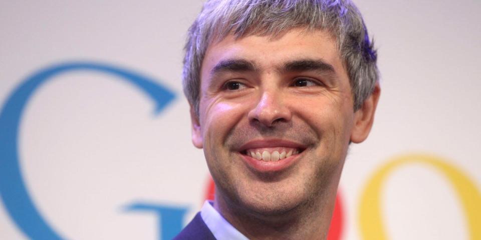 Larry Page smiling with the Google logo behind him.