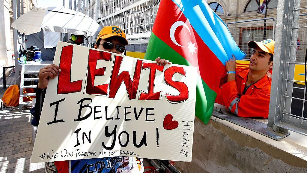 A marshal holds a sign that says "Lewis, I believe in you", while a second marshal holds the Azerbaijan flag 