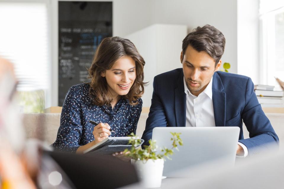 Two investors study something on a laptop.