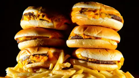 PA Six burgers stacked on top of a pile of chips, they and other fast foods are among those that will be affected by the new rules