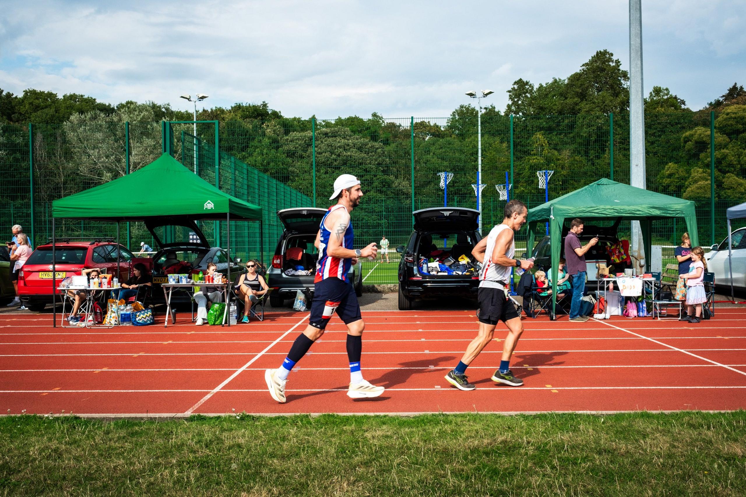 Richard Hall-Smith (left) runs past support crews and aid stations during the Sri Chinmoy 24hr Track Race in Battersea