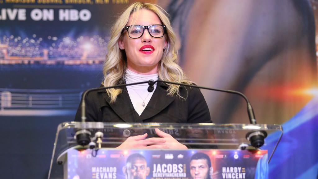 Heather Hardy stands at a microphone