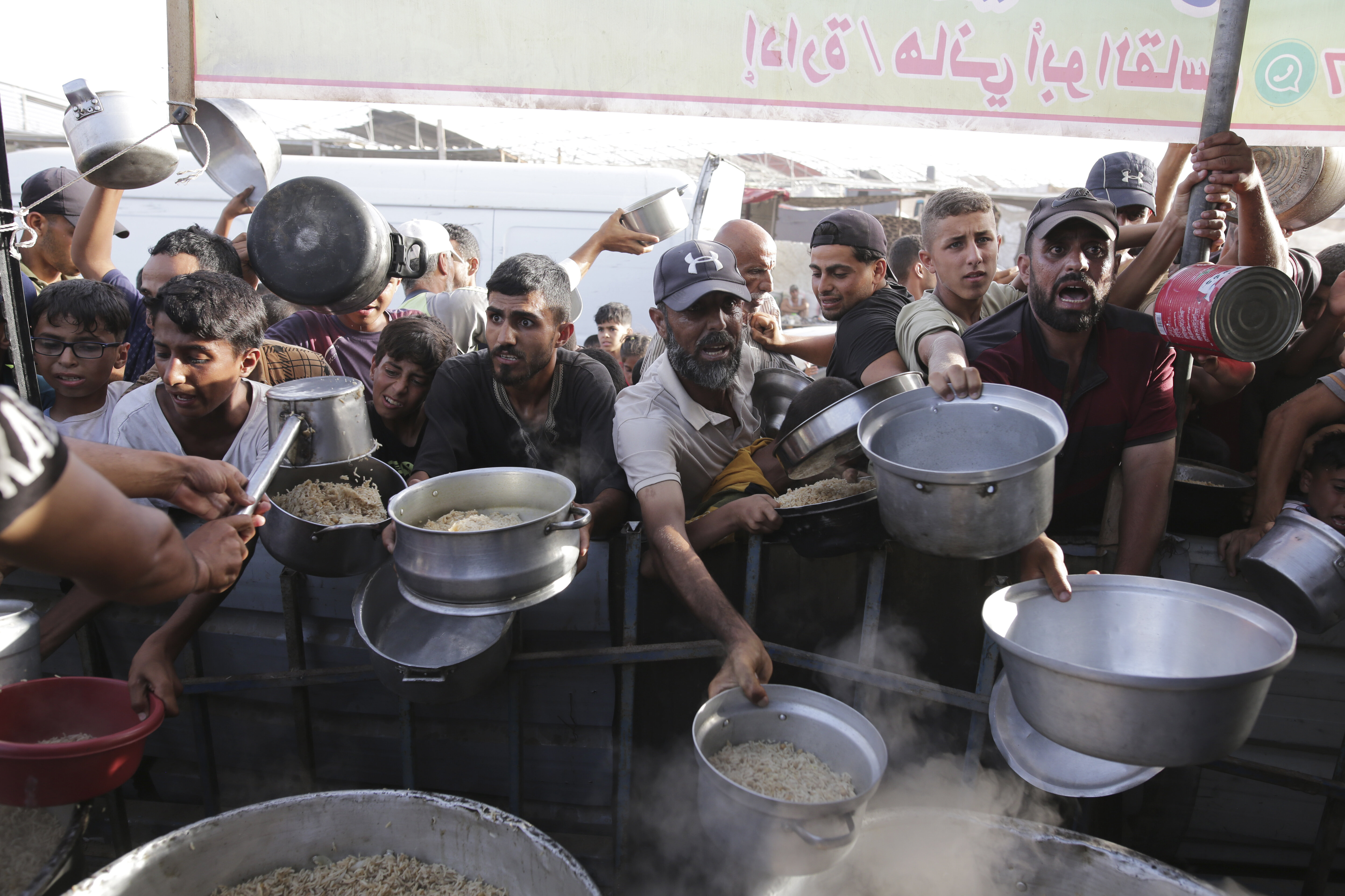 Palestinian men collect food aid ahead of the Eid al-Adha holiday in Khan Younis, Gaza Strip, on June 15, 2024. 