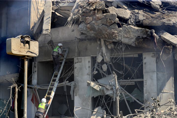 Hezbollah rescue workers search for victims on a destroyed building at commercial street that was hit Saturday night by Israeli airstrikes, in Nabatiyeh town, south Lebanon, Sunday, Oct. 13, 2024. (AP Photo/Mohammed Zaatari)