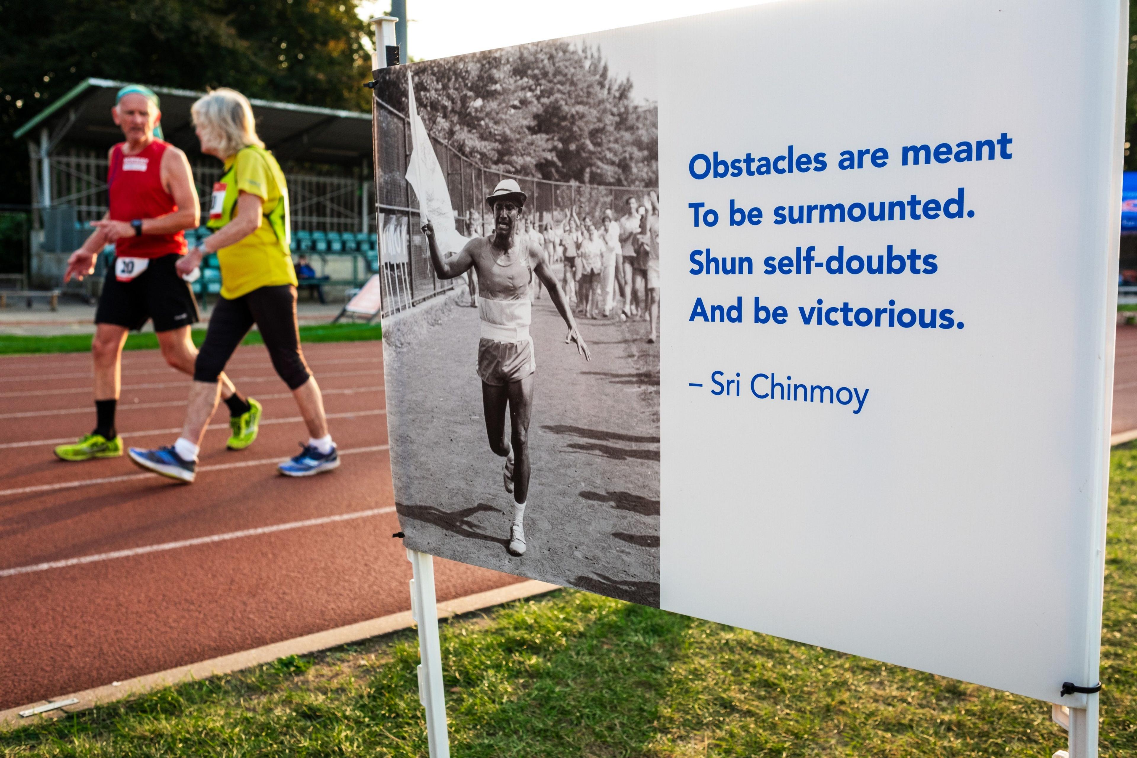 Per Audun Heskestad and Patricia Seabrook walk past a motivational sign during the Sri Chinmoy 24hr Track Race in Battersea