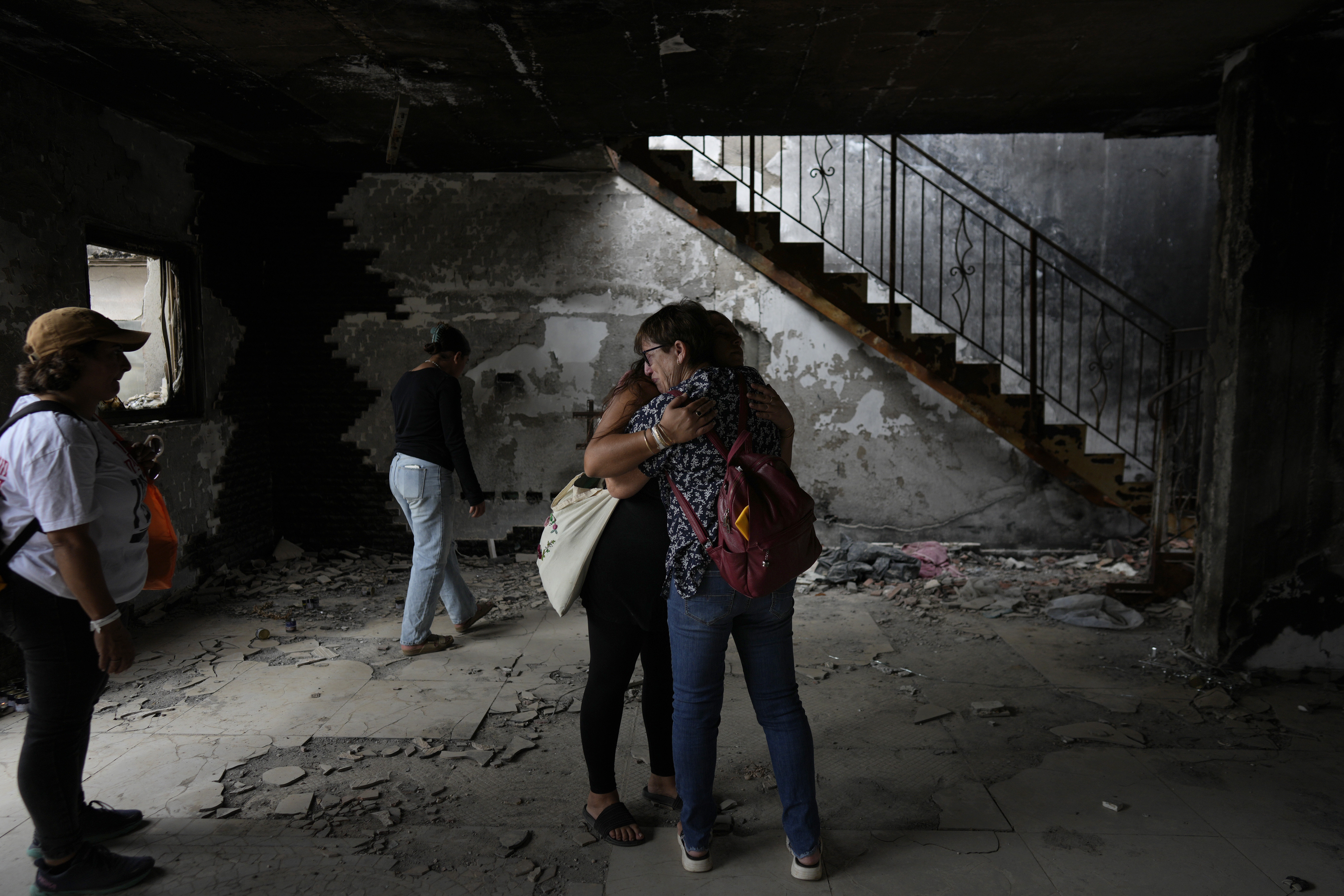 People hug at the house of Maayan and Yuval Bar killed by Hamas, as Israel marks the one-year anniversary of the Hamas attack on Israel, at the Kibbutz Be'eri, an Israeli communal farm on the Gaza border, on Monday, Oct. 7, 2024. (AP Photo/Ohad Zwigenberg)