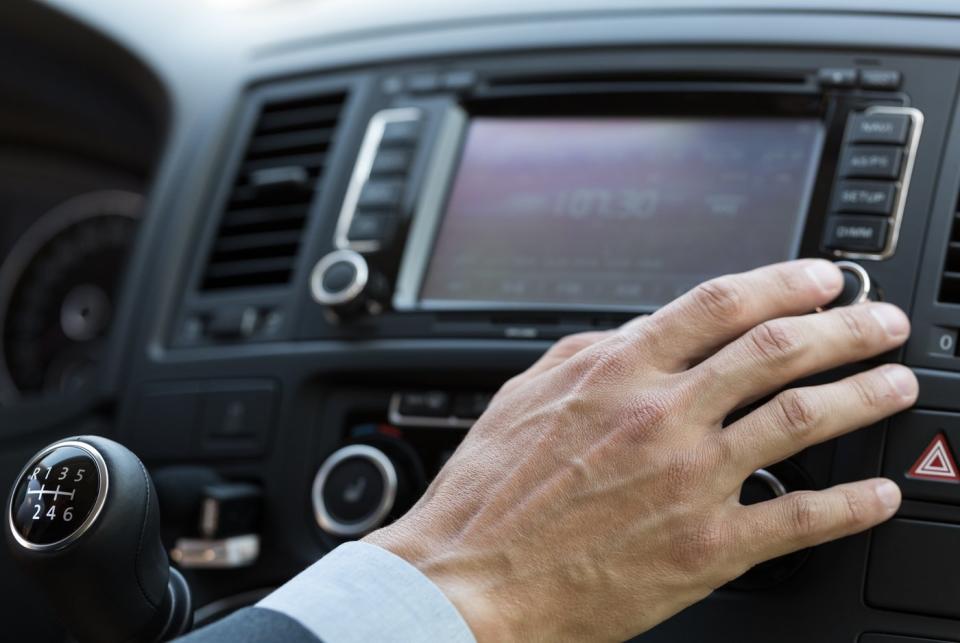 A person pressing a button on their in-car dashboard. 