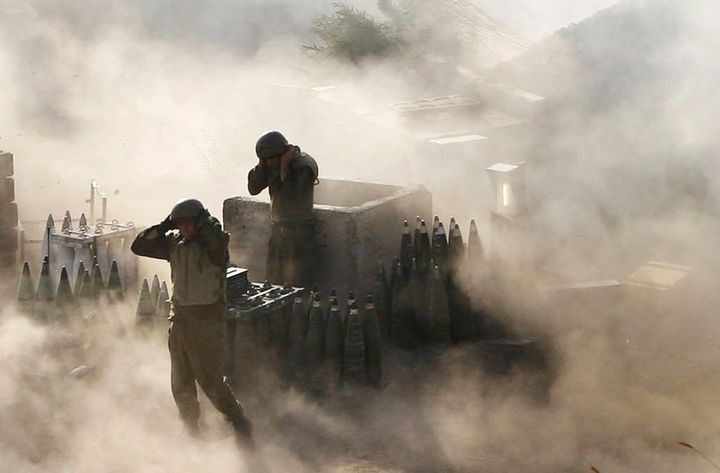 Israeli soldiers are surrounded by smoke and dust as they fire across the border into southern Lebanon from the frontier in Zaura, northern Israel, on July 12, 2006.