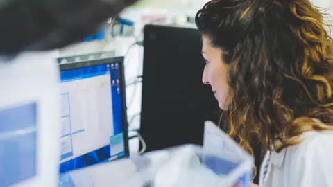 Getty Images A woman looks at a computer screen in a lab setting, image is a generic stock photo and for illustrative purposes only.