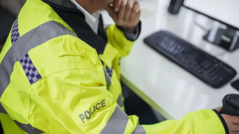 Getty Images Anonymous picture of a police officer looking at a computer in a police station 