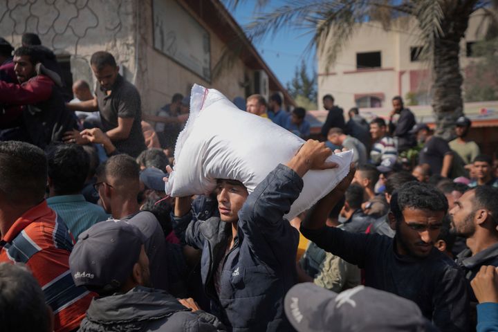 Palestinians gather to receive bags of flour distributed by UNRWA, the U.N. agency helping Palestinian refugees, in Deir al Balah, central Gaza Strip, Saturday, Nov. 2, 2024. (AP Photo/Abdel Kareem Hana)