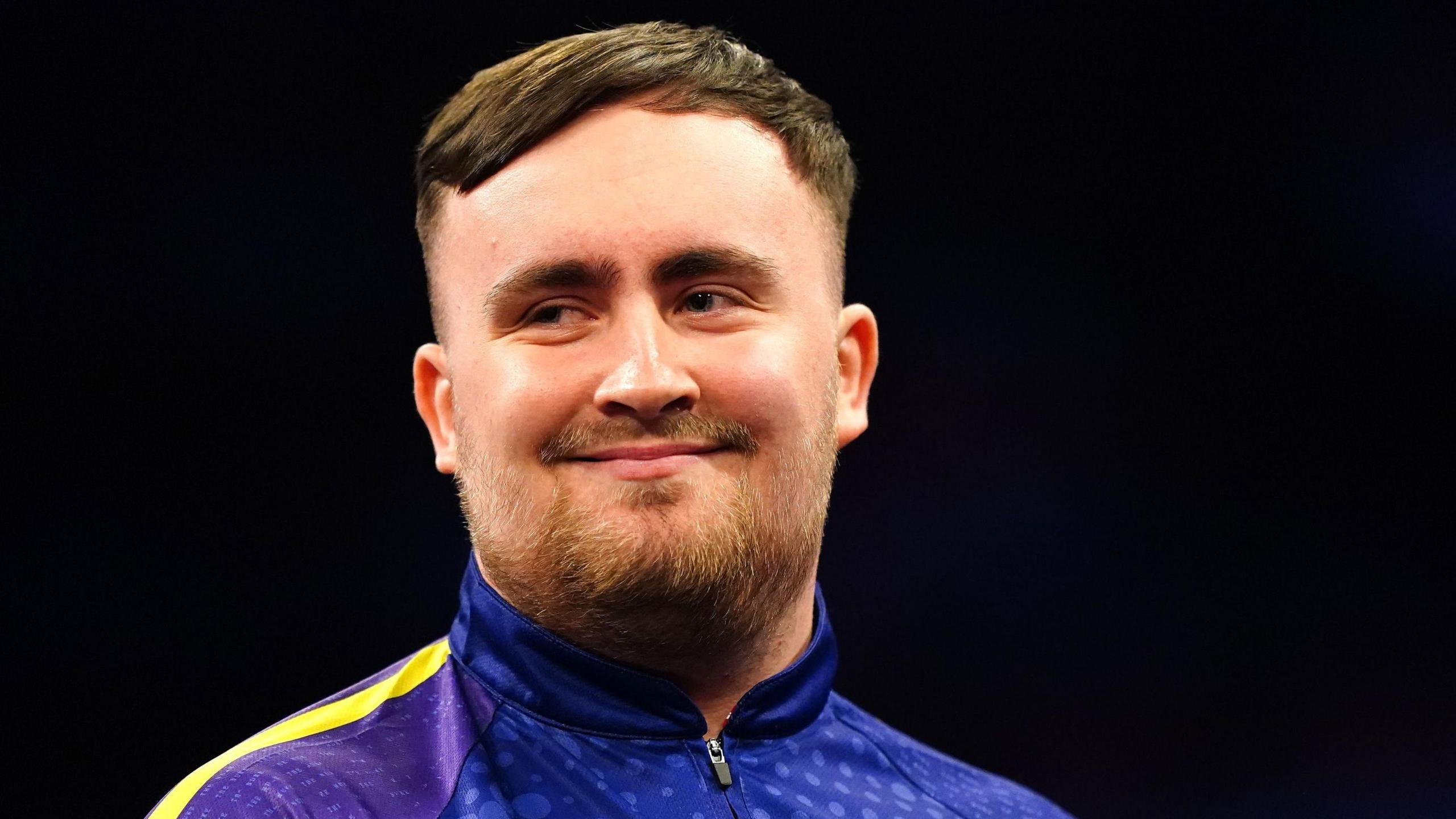 Luke Littler smiles on the oche