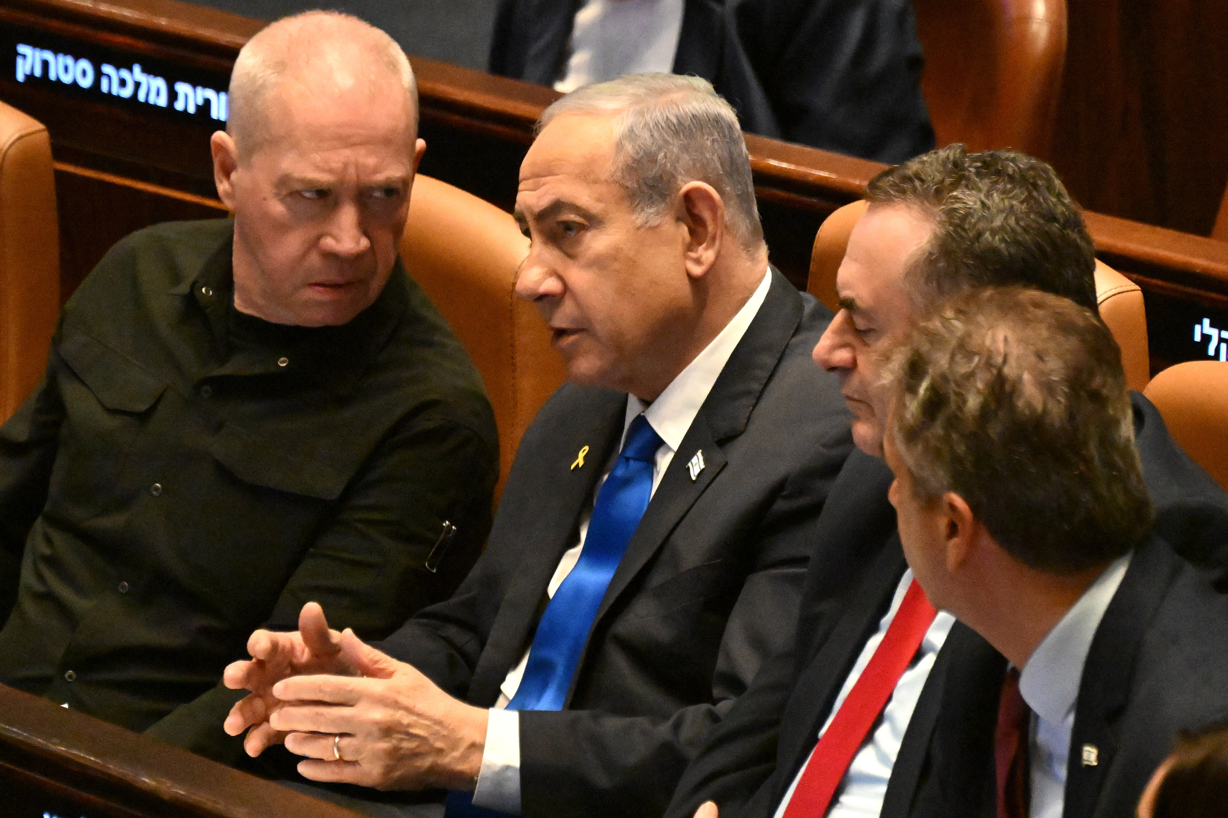 Israeli Prime Minister Benjamin Netanyahu (C) speaks to Defence Minister Yoav Gallant (L) at the opening of the 25th Parliament session in Jerusalem on October 28, 2024. (Photo by DEBBIE HILL / POOL / AFP) (Photo by DEBBIE HILL/POOL/AFP via Getty Images)