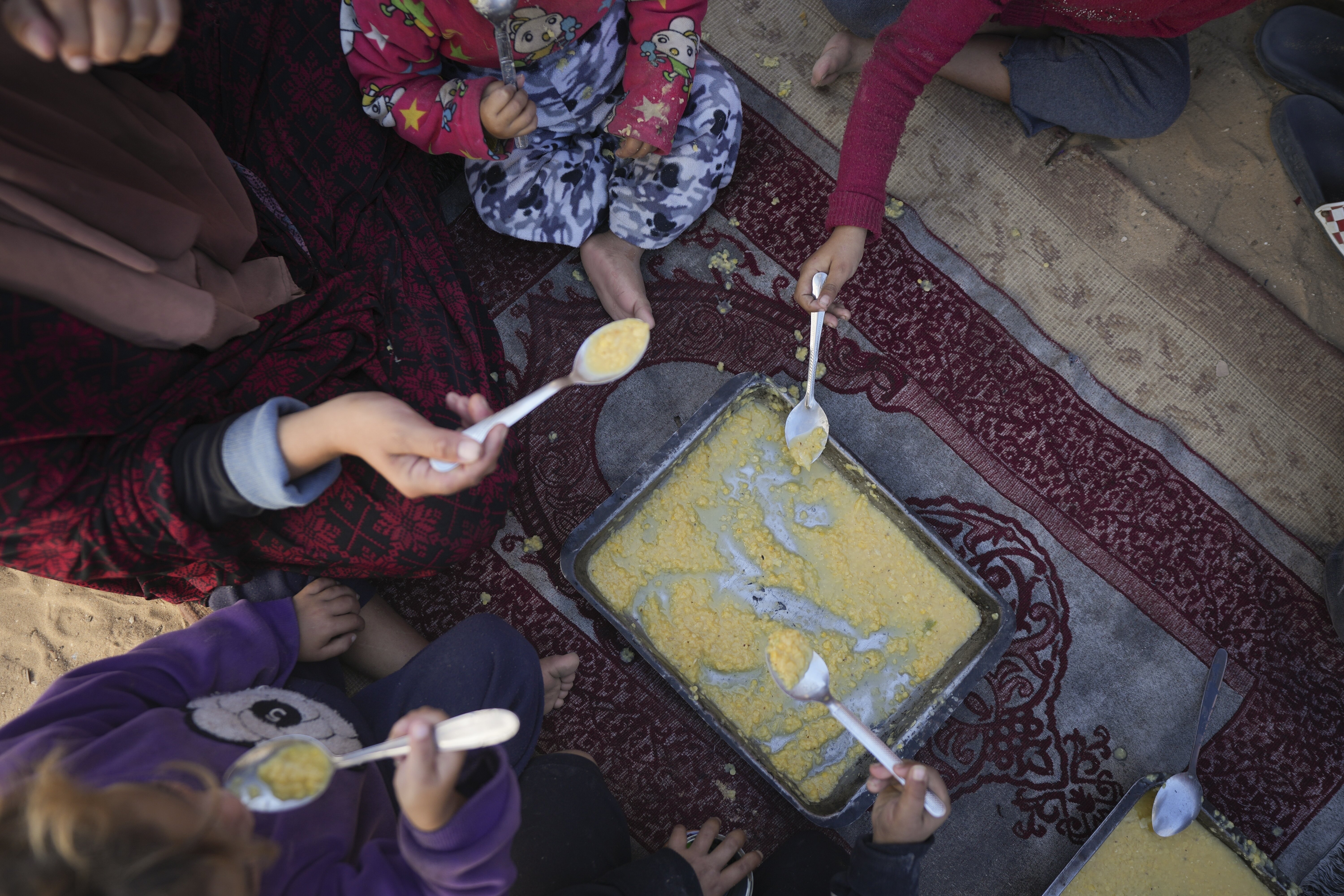 Yasmin Eid and her four daughters eat lentils at their tent in a refugee camp in Deir al-Balah, Gaza Strip, Tuesday, Nov. 19, 2024.