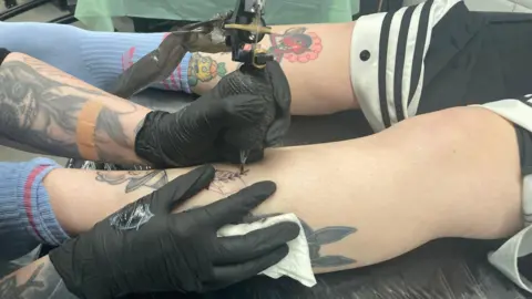 Customer getting a tattoo in Newport, the artist wears black gloves and draws a leaf pattern