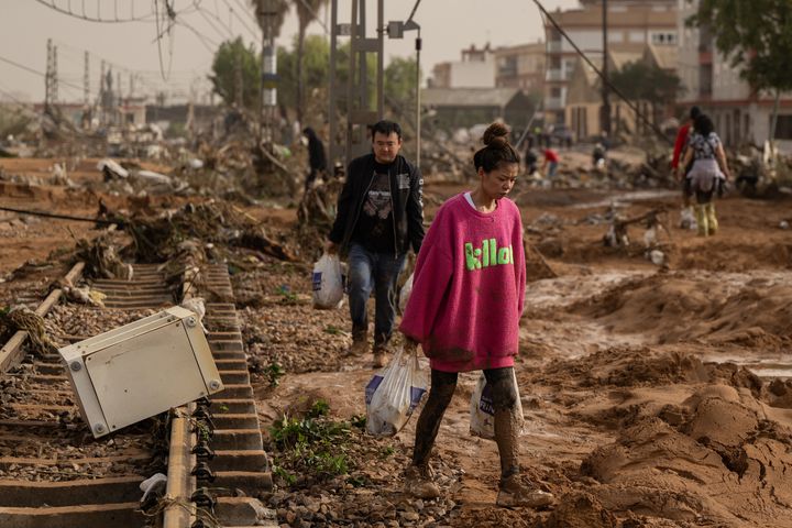 A woman walks along train tracks covered in debris after flash-flooding hit the region of Valencia.