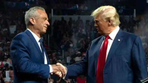 Getty Images Former Republican presidential candidate Robert F. Kennedy Jr. and Republican presidential nominee, former U.S. President Donald Trump shake hands during a campaign rally at Desert Diamond Arena on August 23, 2024 in Glendale, Arizona