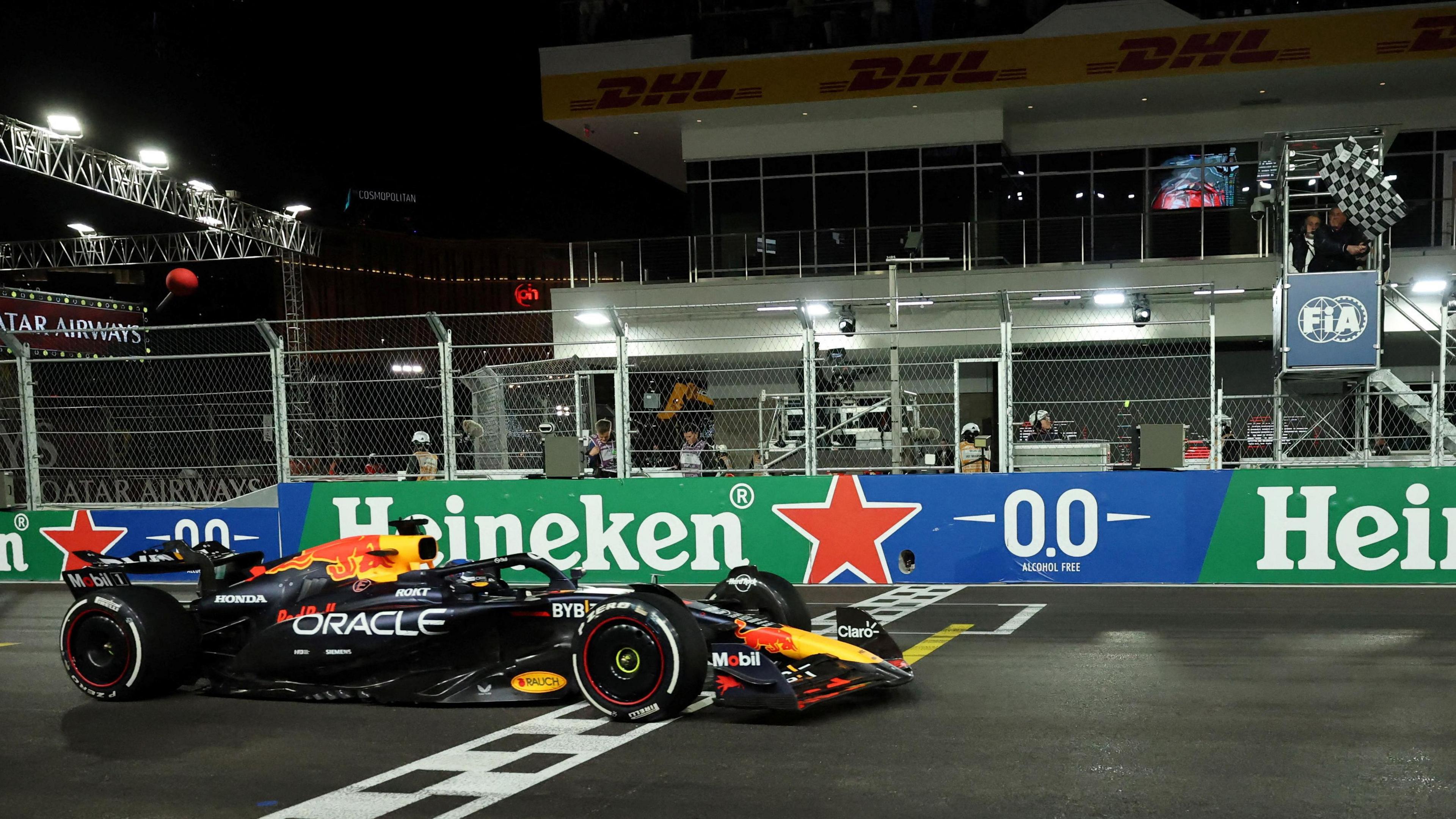 Max Verstappen crosses the finish line at the Las Vegas Grand Prix to win the world title with actor Sylvester Stallone waving the chequered flag