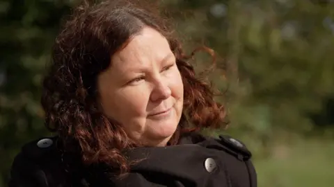 BBC Cassandra Wardle looks off frame with a black coat in a countryside background